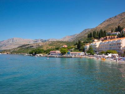 Coastal town with cliffs, blue sea, and hotel buildings under clear sky.