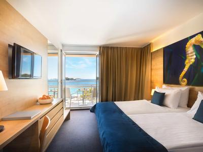 Hotelzimmer mit Doppelbett, Balkon und Meerblick bei Tageslicht