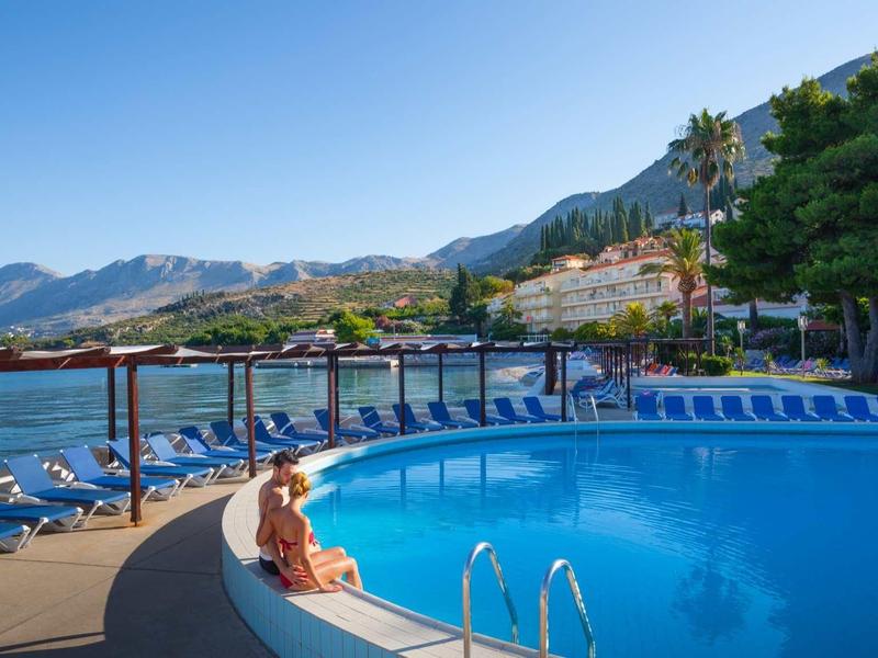 Round pool with sun loungers and sea view against mountains and clear sky
