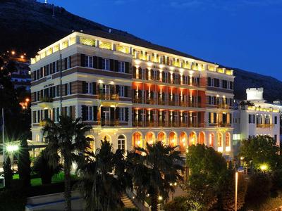 Edificio dell'hotel illuminato su più piani di notte con sfondo montano.