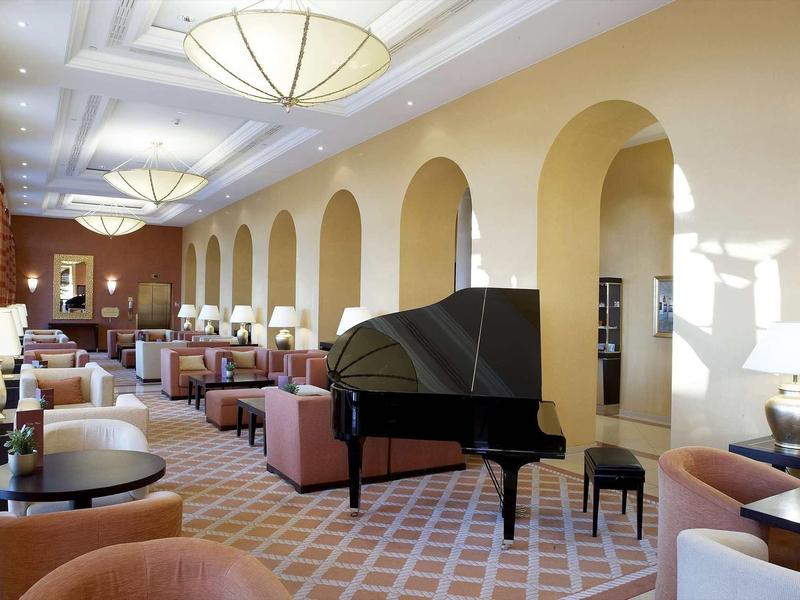 Elegante hall d'hotel con pianoforte a coda e comodi posti a sedere con luce calda.