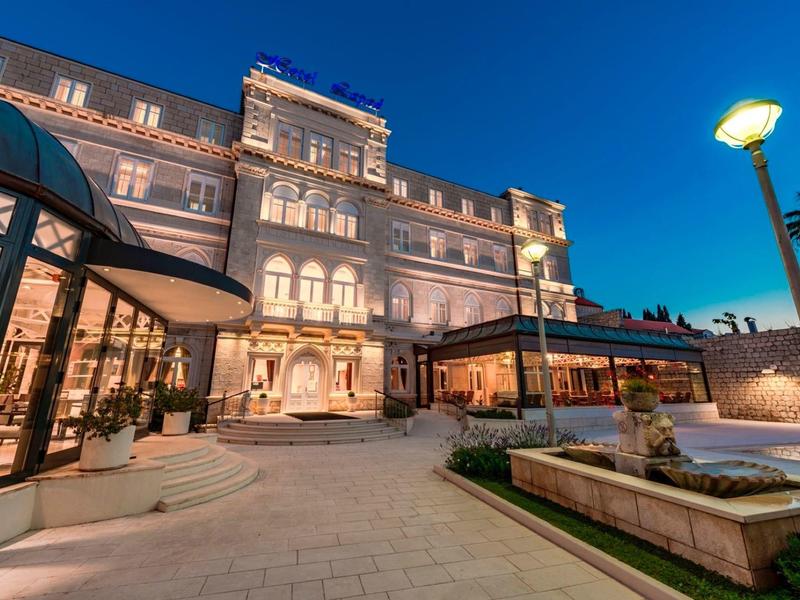 Elegante edificio dell'hotel al crepuscolo con ingresso illuminato e terrazza.