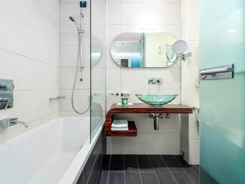 Bagno moderno in hotel con vasca, lavabo in vetro e doccia in vetro