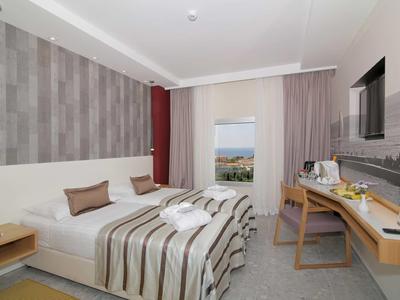 Camera d'hotel moderna con letto matrimoniale, scrivania e vista mare.