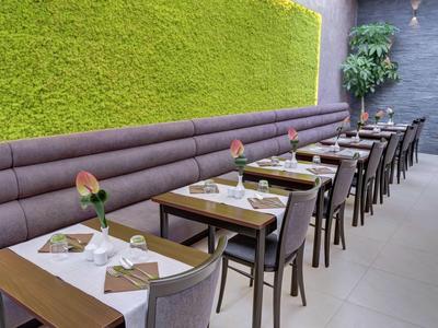 Area pranzo moderna con parete verde e decorazioni sui tavoli in un hotel.