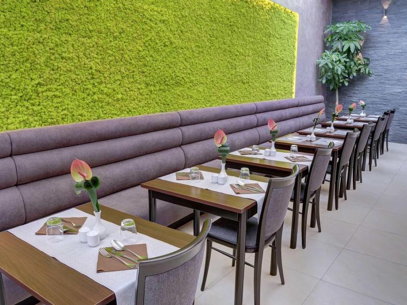 Area pranzo moderna con parete verde e decorazioni sui tavoli in un hotel.