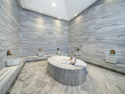 Interno di un hammam con sedute in pietra e vasca centrale.