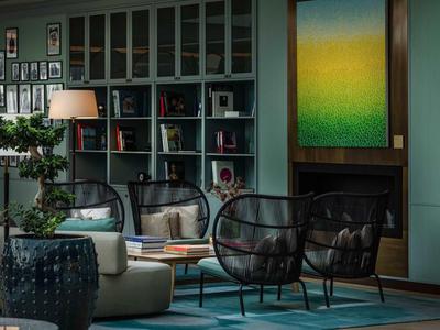 Gemütlicher Hotel-Loungebereich mit modernen Sesseln, Bücherregalen und Kunst an der Wand.