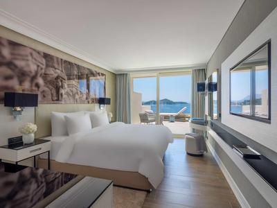 Camera d'albergo moderna con letto grande e vista sul mare tramite ampie finestre.