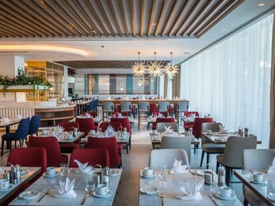 Ristorante elegante con tavoli apparecchiati e grandi finestre in un hotel moderno.