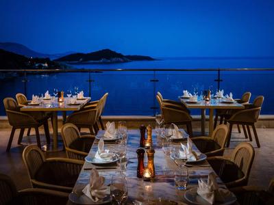 Elegantes Restaurant auf Terrasse mit Blick auf das Meer bei Nacht.