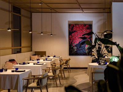 Elegantes Restaurant mit gedeckten Tischen, moderner Beleuchtung und Kunst an der Wand.