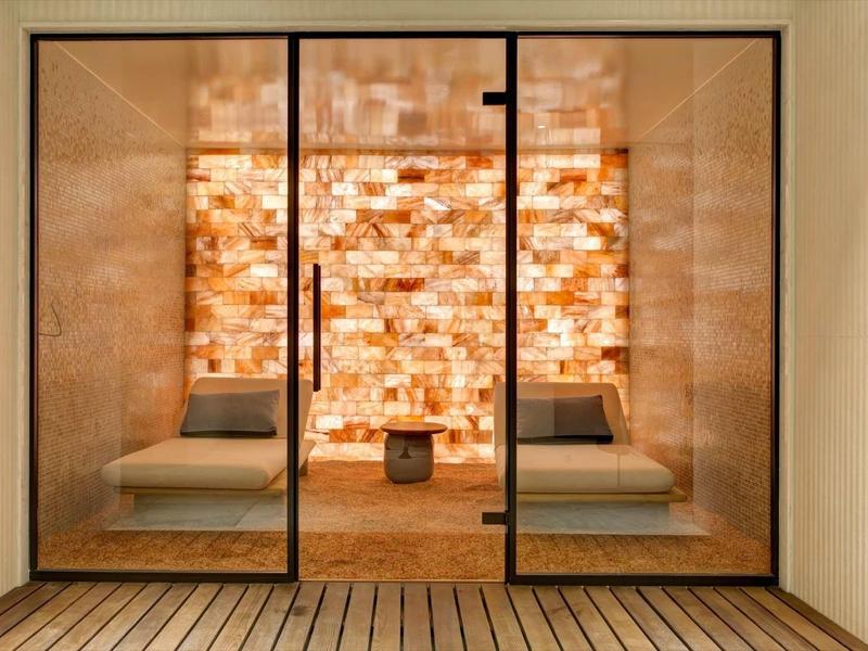Area benessere moderna con parete di sale, lettini e pavimento in legno