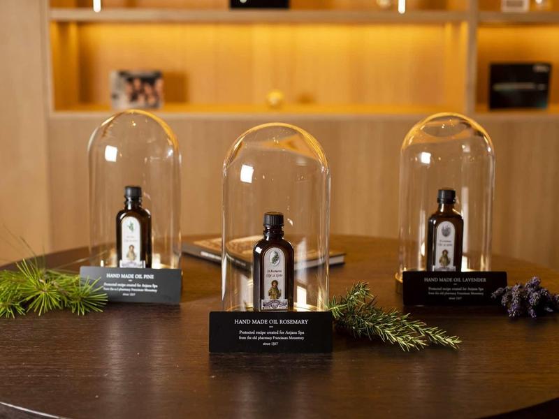 Tre flaconi di profumo sotto campane di vetro su un tavolo di legno.