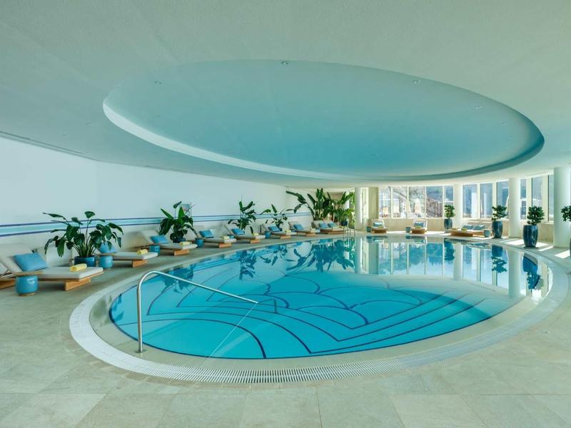 Piscina interna moderna di forma rotonda con piante e grande finestra rotonda sul soffitto
