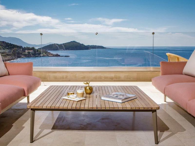 Terrazza con due divani rosa e vista sul mare con cielo limpido.