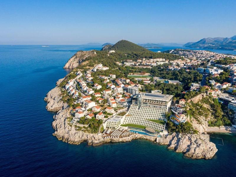Veduta aerea di una città costiera con hotel, spiagge e mare azzurro limpido.