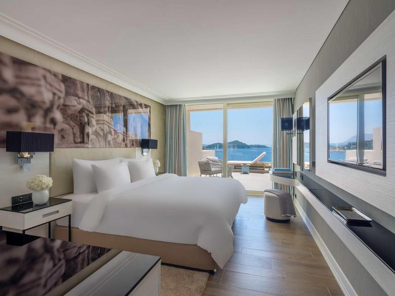 Camera d'albergo moderna con letto grande e vista sul mare tramite ampie finestre.