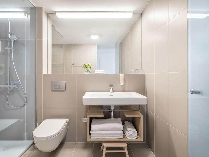 Bagno moderno con toilette, lavabo e doccia, design luminoso e pulito.