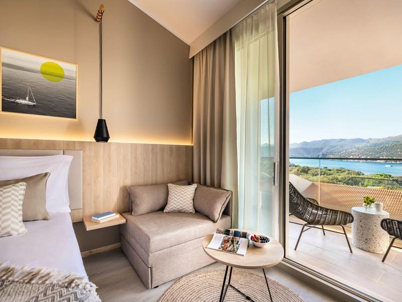 Camera d'hotel moderna con divano a due posti, letto e balcone con vista sul mare.