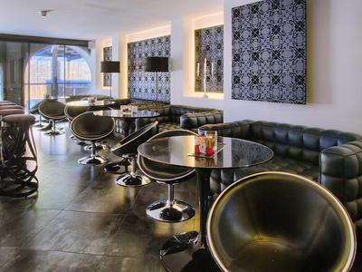 Modern hotel restaurant with black leather chairs and tables, bright wall decorations.