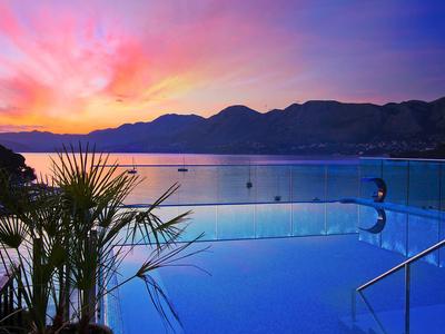 Infinity pool overlooking mountains and sea at colorful sunset