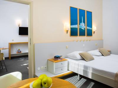 Camera arredata modernamente con letto matrimoniale, comodino e quadro a tre parti.