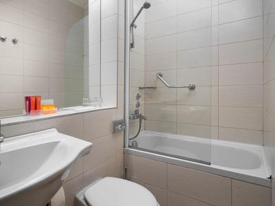 Accogliente area d'attesa con sedie, piante e zona bambini davanti a muro blu in hotel.