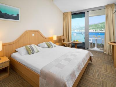Camera d'hotel luminosa con letto matrimoniale e balcone con vista mare.