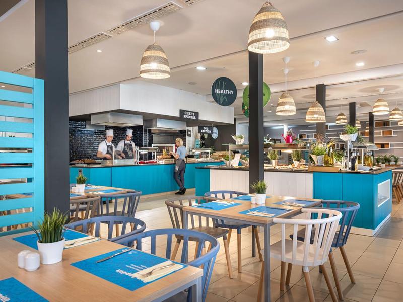 Ristorante moderno con banconi blu, tavoli e sedie in legno in un ambiente luminoso.
