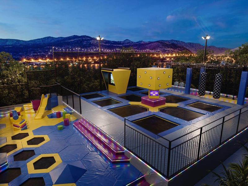 Moderna terrazza sul tetto con area giochi e vista sulla città illuminata di notte.