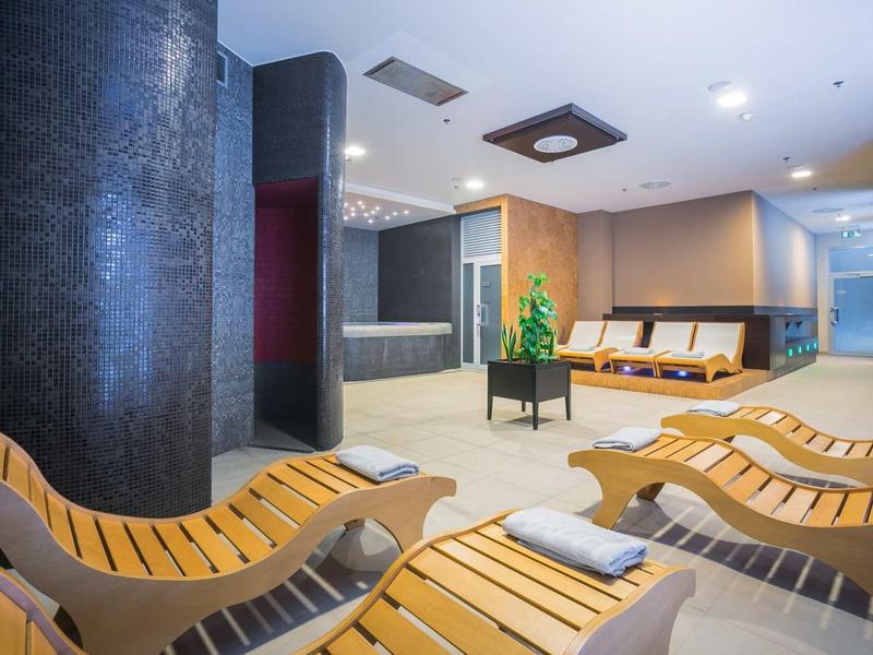 Lounge spa moderno con sedie reclinabili in legno, asciugamani e luce soffusa.