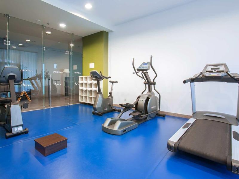 Palestra luminosa con macchine cardio e pavimento blu in un hotel moderno.