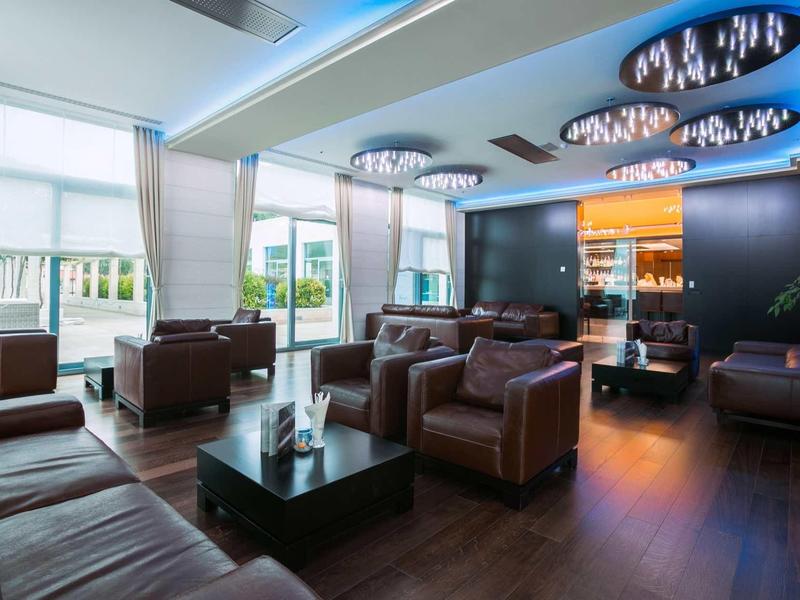 Lounge moderno dell'hotel con divani in pelle, poltrone, grandi finestre e illuminazione elegante.