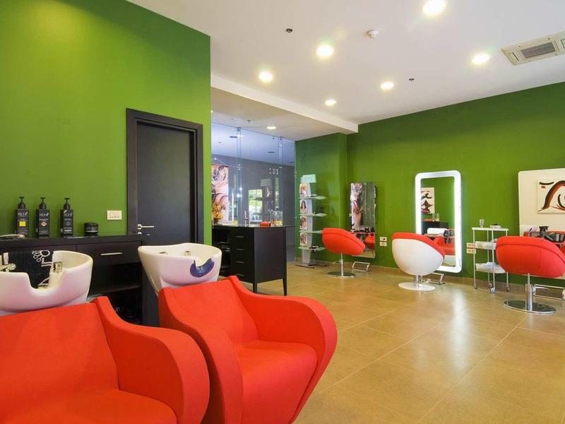 Salone verde e rosso con poltrone comode e postazioni di styling moderne.