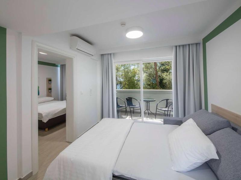 Modern hotel room with double bed, sofa, and balcony with chairs and table
