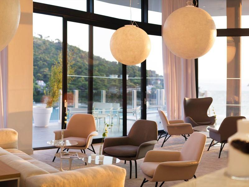 Area lounge moderna e luminosa dell'hotel con lampade rotonde e vista sulla natura.