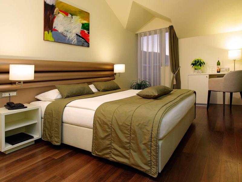 Camera d'hotel moderna con letto matrimoniale, comodini e area lavoro.