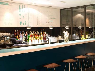 Moderní hotelový bar s pultem, barovými židlemi a různými nápoji.