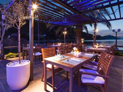 Večerní terasa s prostřeným stolem a výhledem na moře pod dřevěnou pergolou.