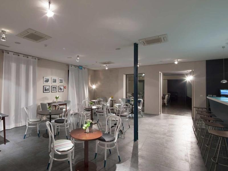 Nowoczesny obszar hotelowy z barem, stołami i krzesłami, subtelne oświetlenie i minimalistyczny design.