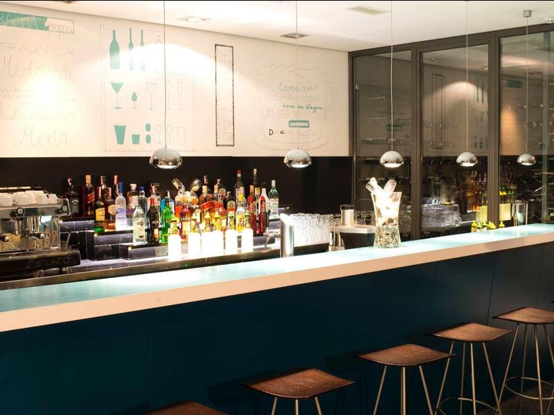 Nowoczesny bar hotelowy z podświetlanym barem, stołkami barowymi i wyborem napojów.