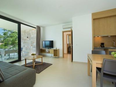 Nowoczesny salon z sofą, stołem jadalnym i dużym oknem z widokiem na taras i morze.