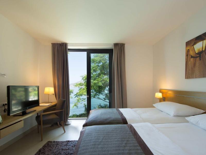 Moderne hotelkamer met twee bedden, bureau, tv en balkon met uitzicht op het meer.