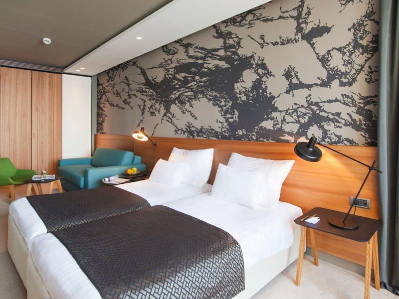 Habitación de hotel moderna con cama doble, decoración de pared elegante y asientos confortables.