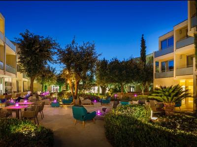 Area esterna illuminata di un hotel con sedute e piante di notte.