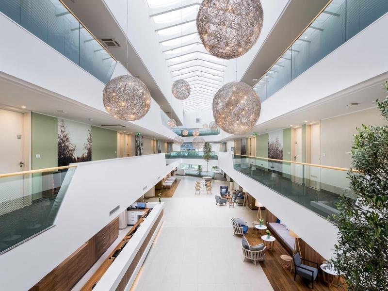 Moderner, heller Innenraum mit großen Kugellampen, Glasgeländern und Sitzbereichen rechts.