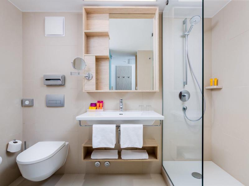 Modernes Badezimmer mit fliegender Toilette, Waschbecken, Spiegel und Duschkabine rechts.