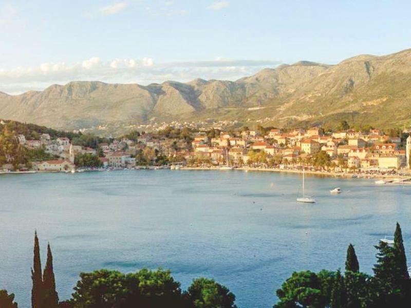 Panoramic view of a bay with a coastal town and mountains in the background