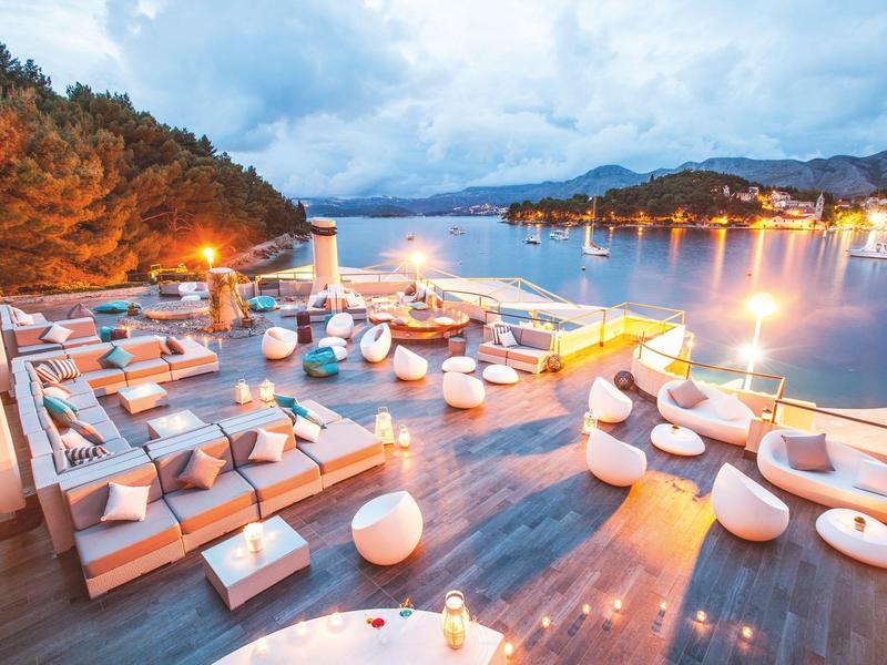 Luxurious rooftop terrace with seating and view of calm sea at dusk.